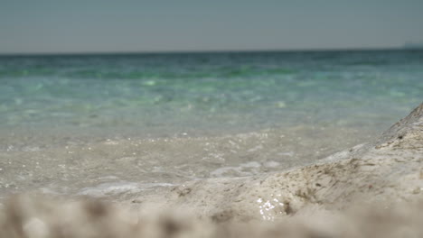 Turquoise-blue-sea-waves-splashing-at-rocky-beach-in-Sicily,-Italy