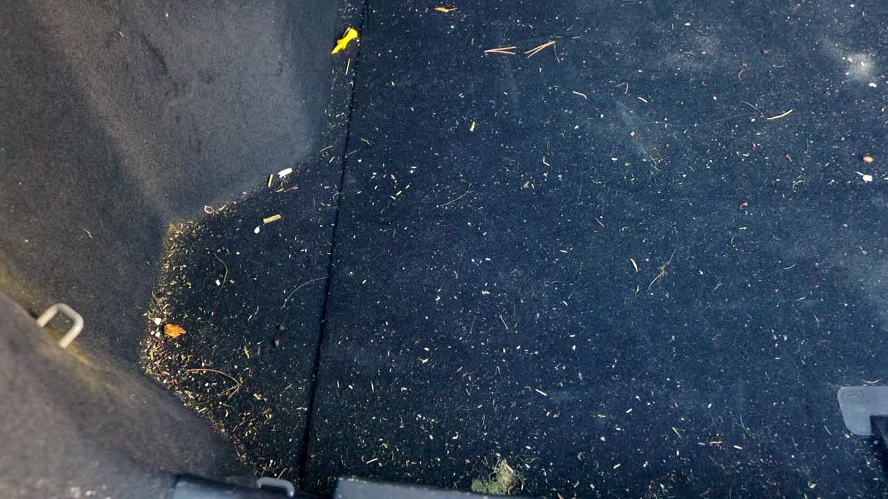 Extremely dirty SUV trunk with hay, straw and plaster in the carpet - panning truck left to right