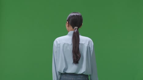 back view of asian business woman walking on green screen background in the studio