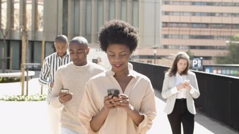 Group-of-young-people-walking-on-street-with-phones