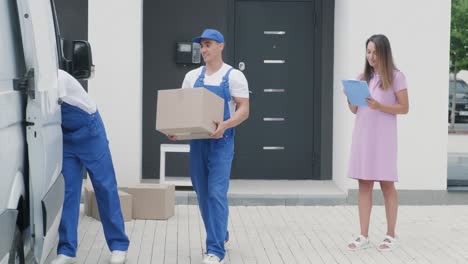 two young workers of removal company are loading boxes into a minibus