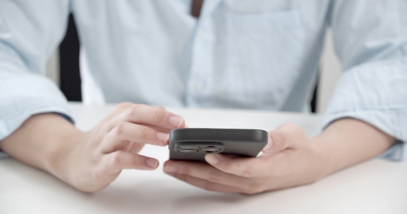 Primo piano della mano di un giovane che tocca con grazia lo schermo del suo telefono da destra a sinistra, mostrando il suo coinvolgimento con i social media tramite piattaforme online. Perfetto per temi di stile di vita digitale.