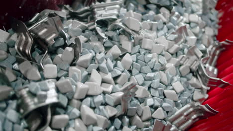 close up of intermediate metal car components being cleaned in a vibrating bed of rocks and soap