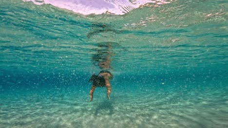 underwater scene of brunette caucasian woman swimming in incredible crystal clear tropical sea water of exotic island