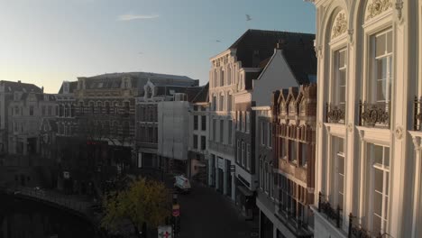 Pasando-Lentamente-Por-Las-Fachadas-Históricas-De-La-Ciudad-De-Utrecht,-En-Los-Países-Bajos,-Iluminadas-Por-Un-Sol-Naciente-Temprano-En-La-Mañana,-Cuando-Las-Calles-Están-Desiertas-Y-Sólo-Un-Equipo-De-Limpieza-Está-Poblando-Las-Calles.