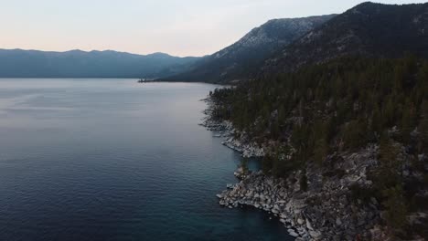 tomada de un dron de la rocosa costa este del lago tahoe y el bosque circundante al atardecer