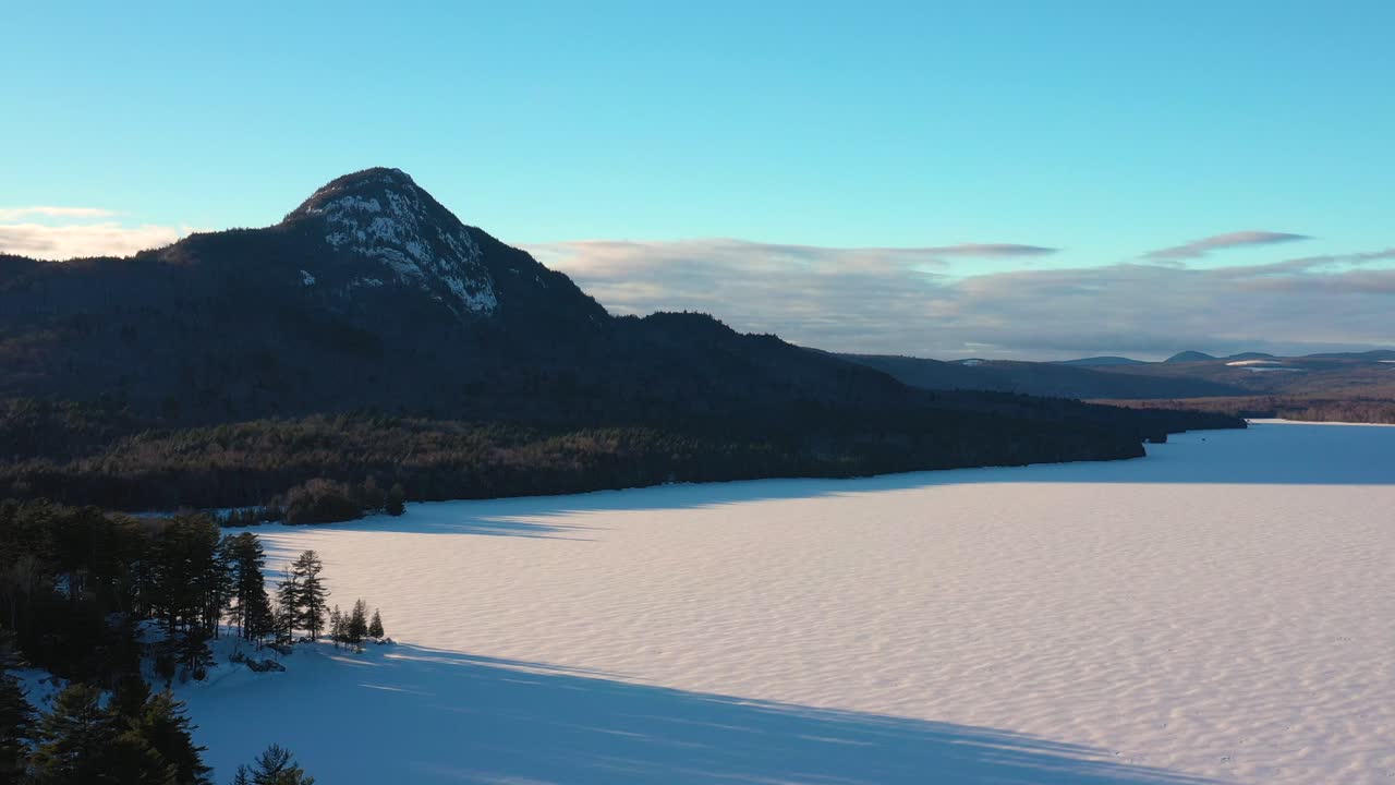 멀리 눈 덮인 산봉우리가 있는 얼어붙은 호수 기슭을 따라 앞으로 날아갑니다.