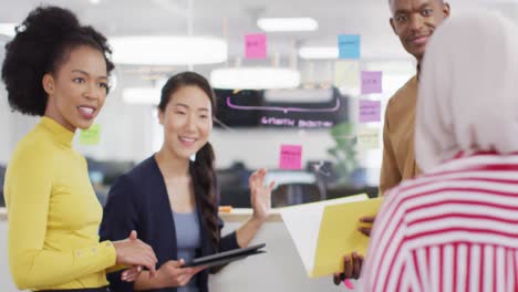 Group-of-diverse-business-people-taking-notes-on-glass-wall-and-talking-in-office,-slow-motion