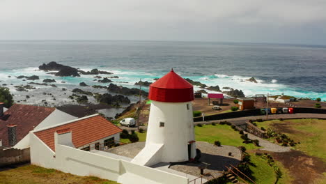 aerial drone show of small white and red lighthouse located at the coastline in sao miguel island in the azores - portugal