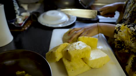 Hände-Schneiden-Gelbe-Ananas-Auf-Einem-Schneidebrett