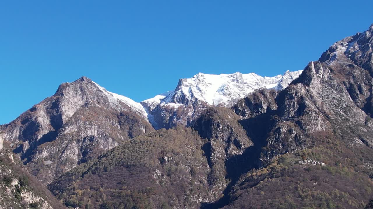 Dramatic aerial view of snow-capped Alps in Italy under clear blue skies