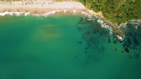 Beruhigende-Luftaufnahme-Von-Wellen,-Die-An-Einem-Sommertag-Entlang-Der-Küste-Plätschern