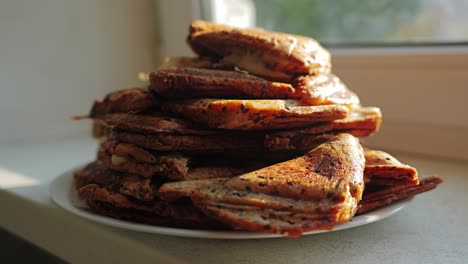 pyramid of toasted sandwiches sits on plate as evening sun stream through window