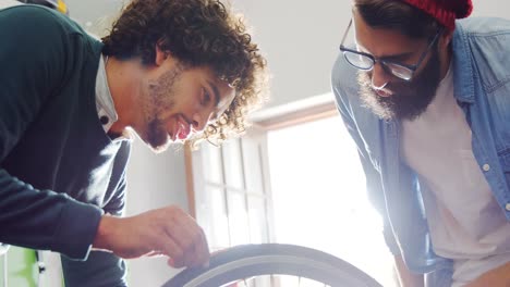 Mechanics-repairing-bicycle-in-workshop