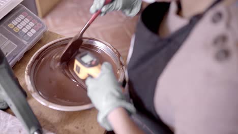 Unrecognizable-confectioner-measuring-temperature-of-chocolate