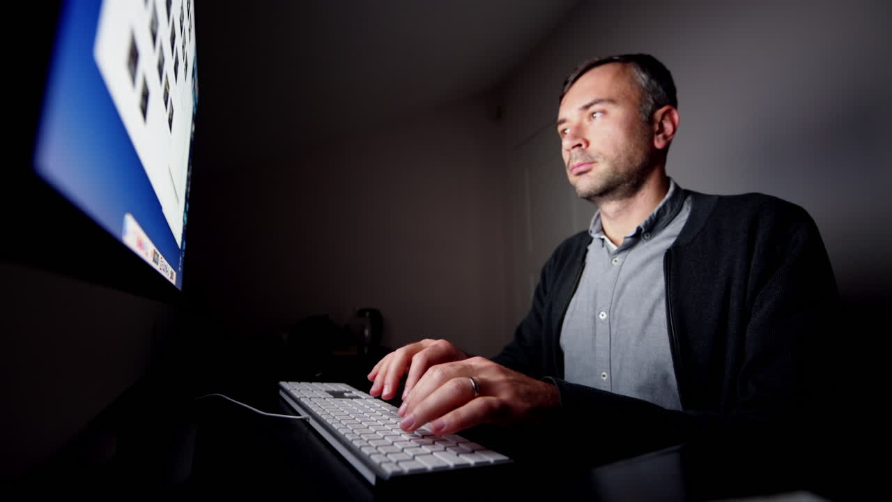 CHISINAU, MOLDOVA - NOVEMBER, 2021: Man working on iMac computer at night, dark room wide view