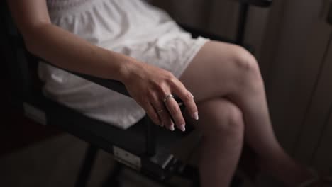 cerca de la mano de una mujer con anillos descansando en un brazo de silla, iluminación natural suave