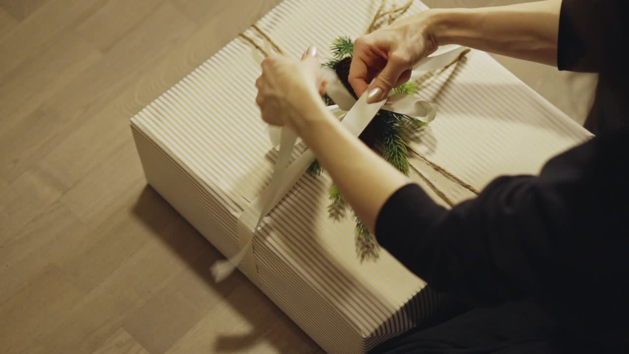 Donna che lega un nastro su un regalo di Natale - Confezionamento regalo fai da te. - primo piano.