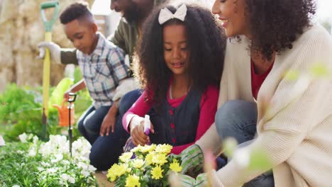 padres afrodescendientes felices con hijos haciendo jardinería juntos