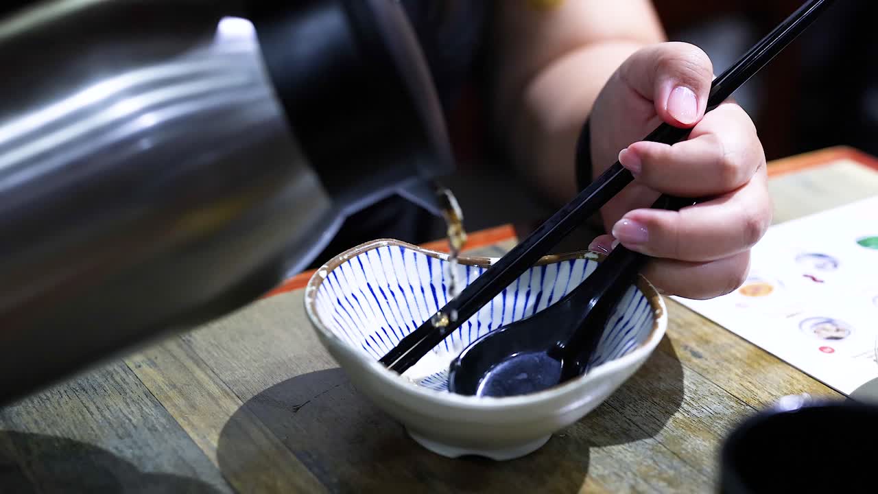 persona vertiendo agua en un cuenco con palillos
