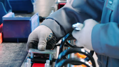 factory worker putting metal pads on bolt. manual work in assembly shop of plant