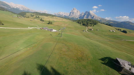 Green-meadows-and-majestic-Dolomites-in-horizon,-aerial-FPV-view