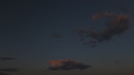 a low angle time lapse, looking up at clouds floating away from the camera, with the golden glow of the sun slowly fading away. the camera is stationary as the clouds float.