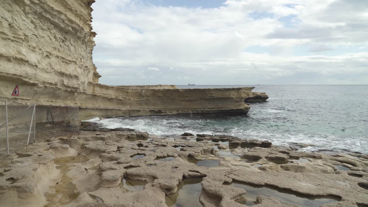 agujeros formados en suelo de piedra lleno de agua en la playa de piedra de la piscina de san pedro en malta