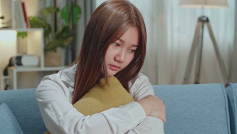 unhappy lonely depressed young asian woman at home, she is sitting on the couch, depression concept