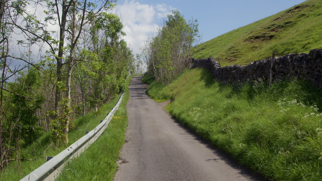 Winding Rural Road Uphill Through Green Countryside