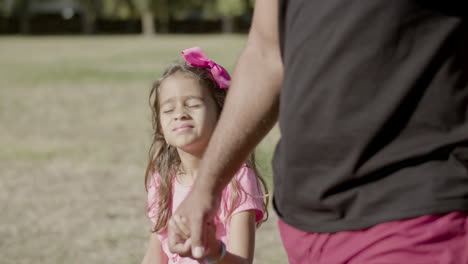 medium shot of daughter walking with dad in summer park