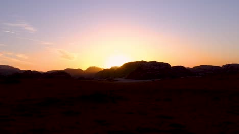 sunset and last rays of sunlight disappearing behind mountains in remote wilderness of wadi rum desert in jordan