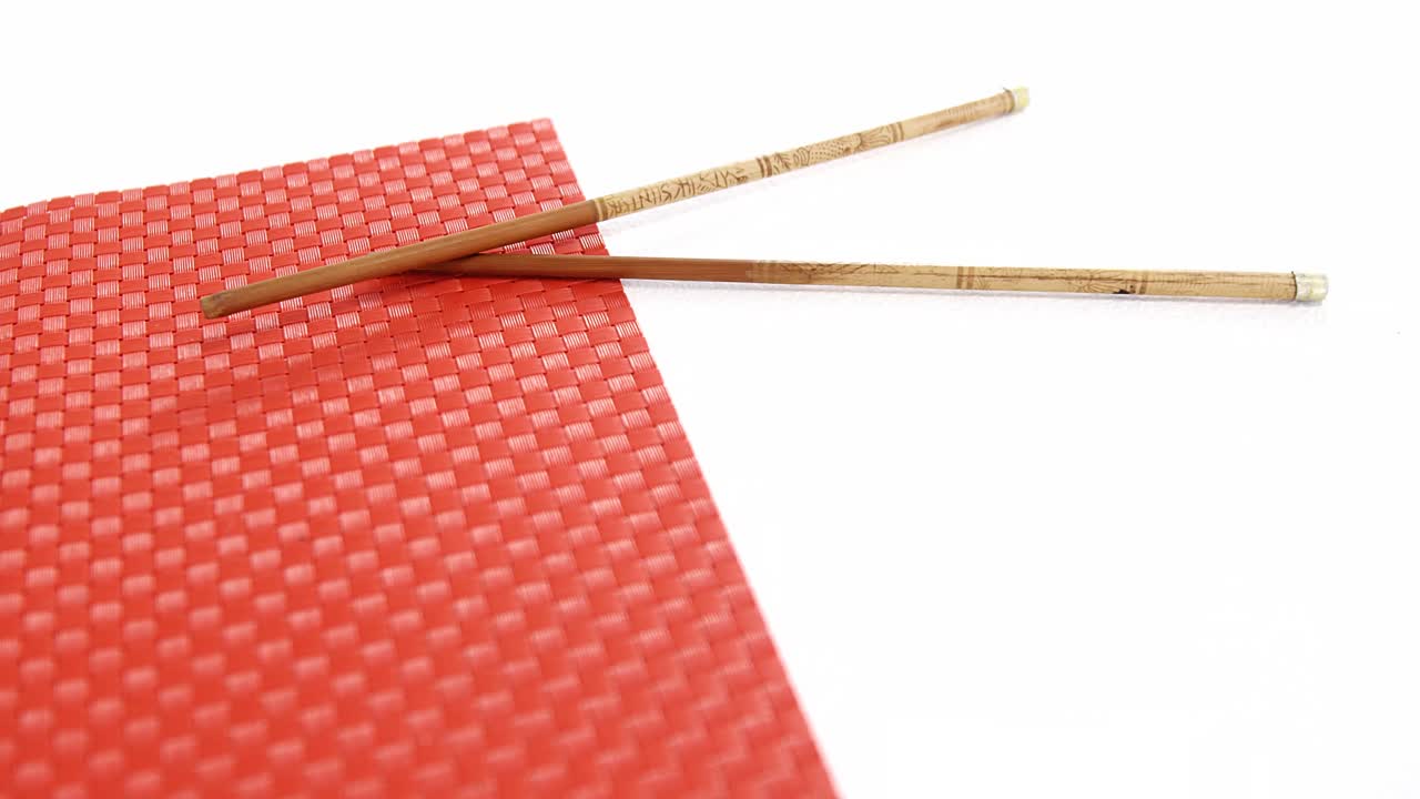 Sushi mat with chopsticks on white background