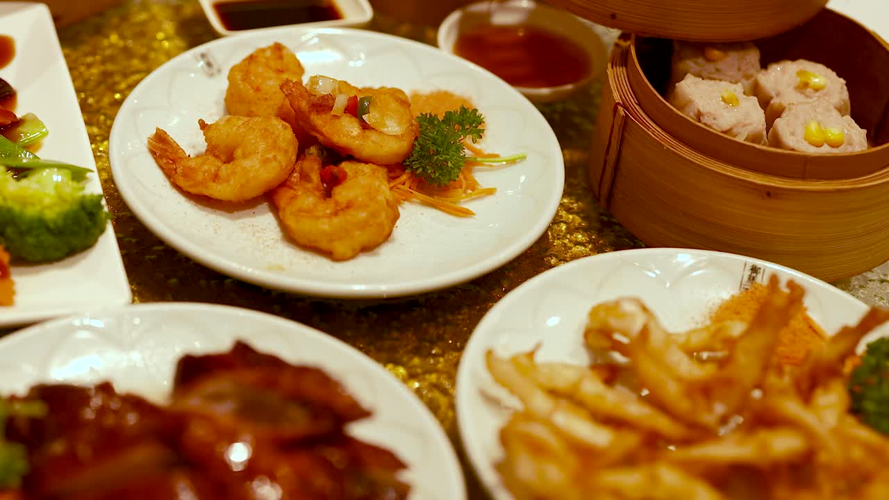 A vibrant spread of dimsum and deep-fried snacks in a Chinese restaurant setting, showcasing shrimp, vegetables, and sauces