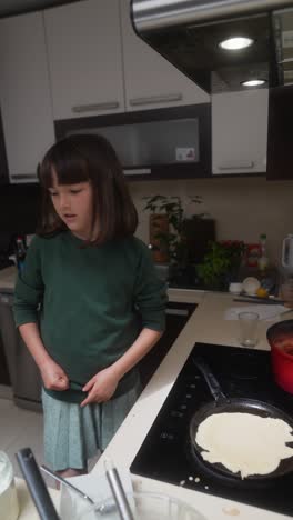 child making pancakes in a kitchen