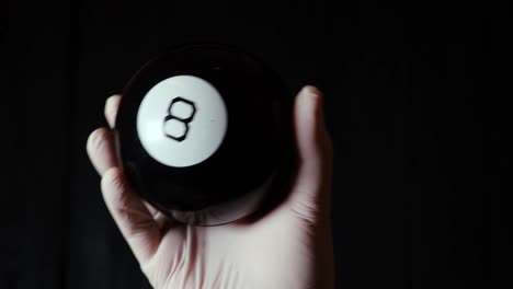 ball of predictions figure eight in hand in a glove on a black background.