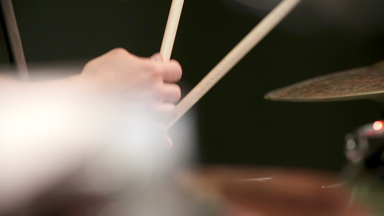 Primo piano della mano di un batterista che suona batteria e piatti