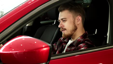 handsome young man sitting comfortably in his new car smiling to the camera