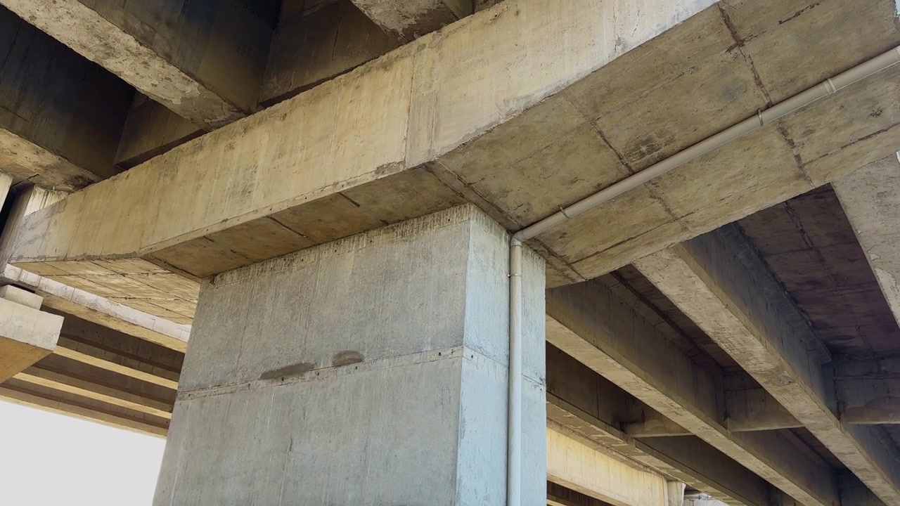 Tilt up shot of a reinforced concrete bridge pier cap supporting multiple girders and deck sections of an elevated roadway highlighting civil engineering design and transportation infrastructure