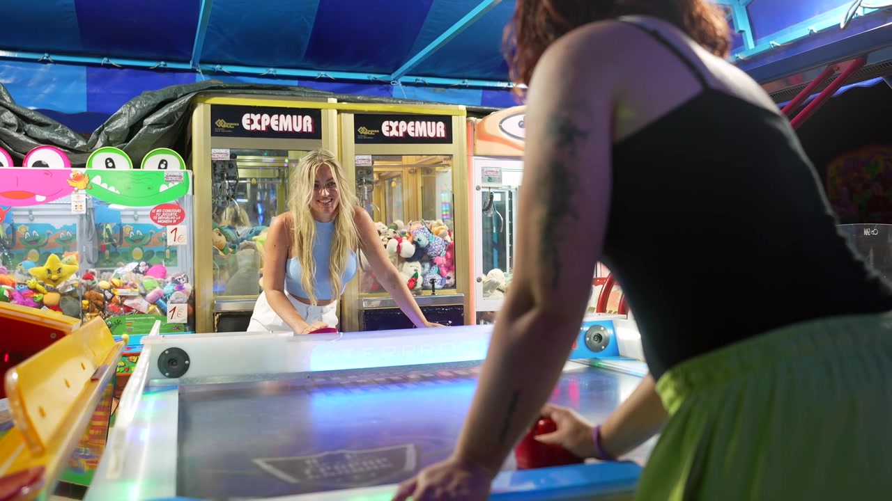 To unge kvinner spiller airhockey i en spillehall