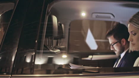 outside view of a moving car, a couple in smart clothes reading documents