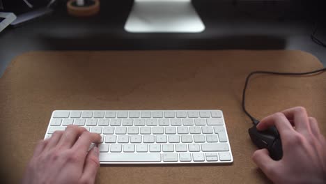 man typing on his keyboard and using his mouse