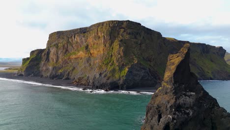 Scenic-aerial-view-of-the-black-sand-beach-and-the-vik-rock-in-Southern-Iceland