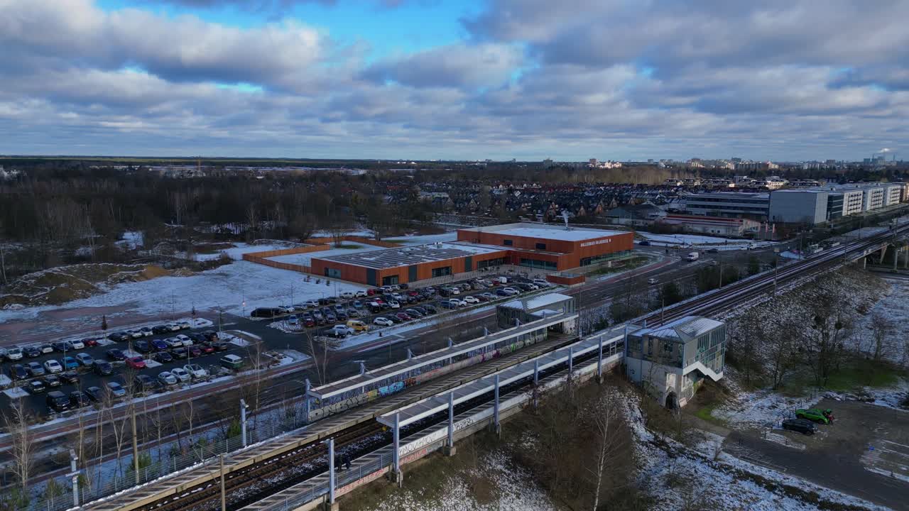 snowy train station with parked cars and surrounding buildings. Nice aerial view flight static tripod hovering drone