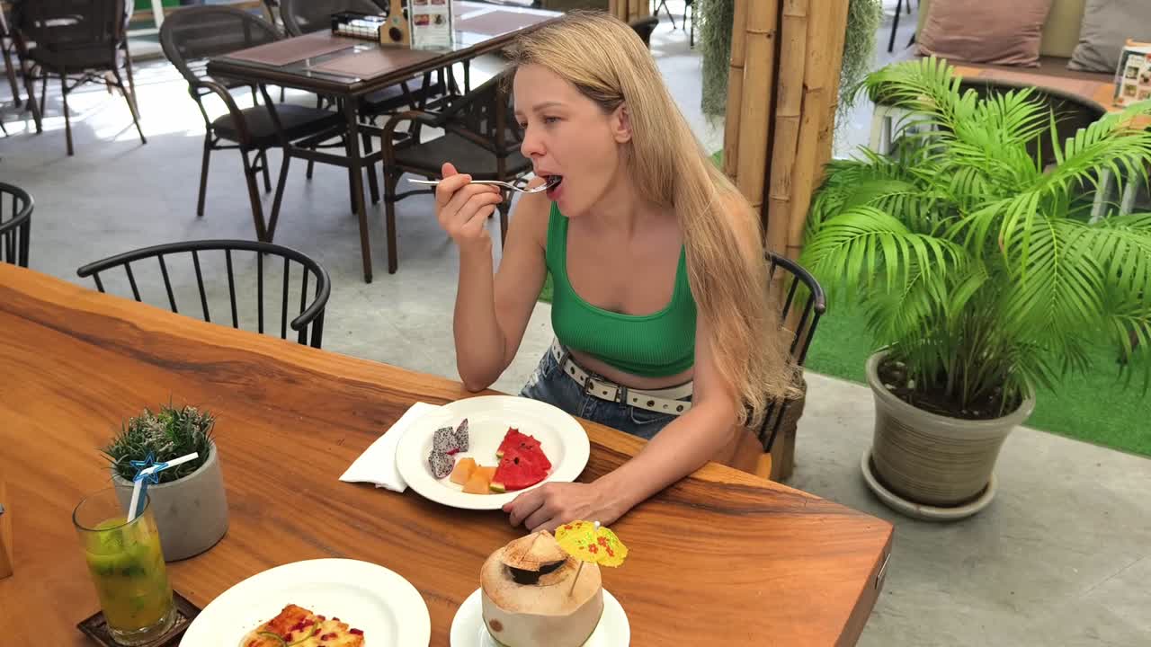 mujer comiendo ensalada de frutas en un restaurante tropical