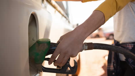 midsection of biracial woman using fuel pump filling up car at petrol station