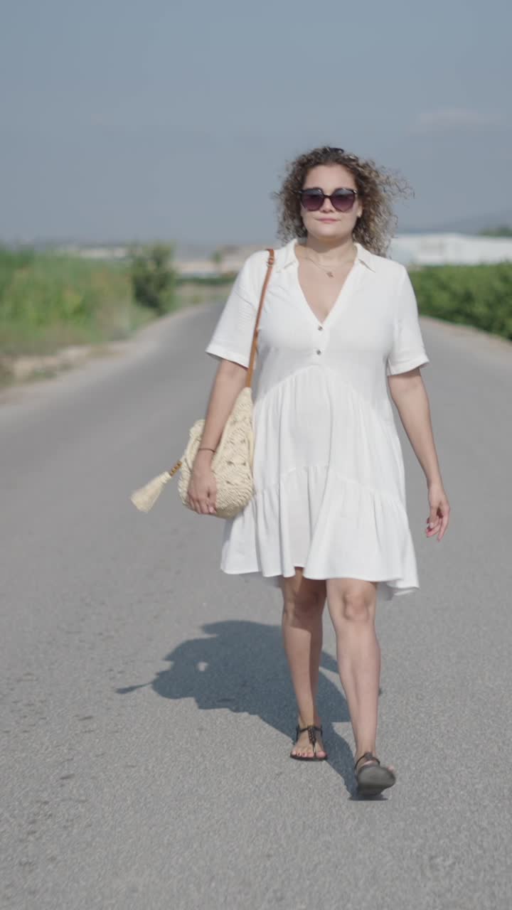 Woman in white dress walking on a road