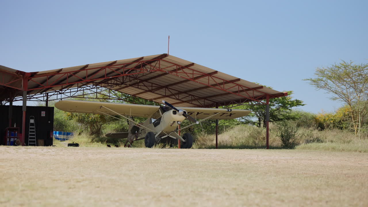 Personale di terra che traina un piccolo aereo a elica da un hangar