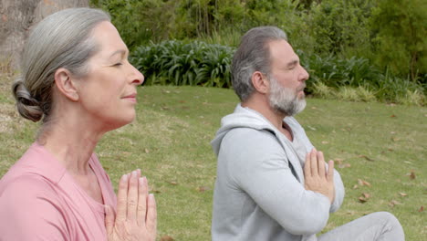 mature couple meditating outdoors, practicing mindfulness in peaceful garden setting