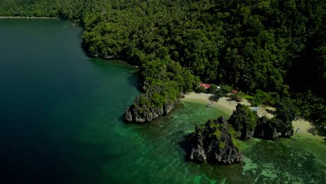 Häuser-Am-Idyllischen-Strand-Und-Grünen-Hügeln-Am-Meer-Auf-Den-Philippinen,-Luftaufnahme